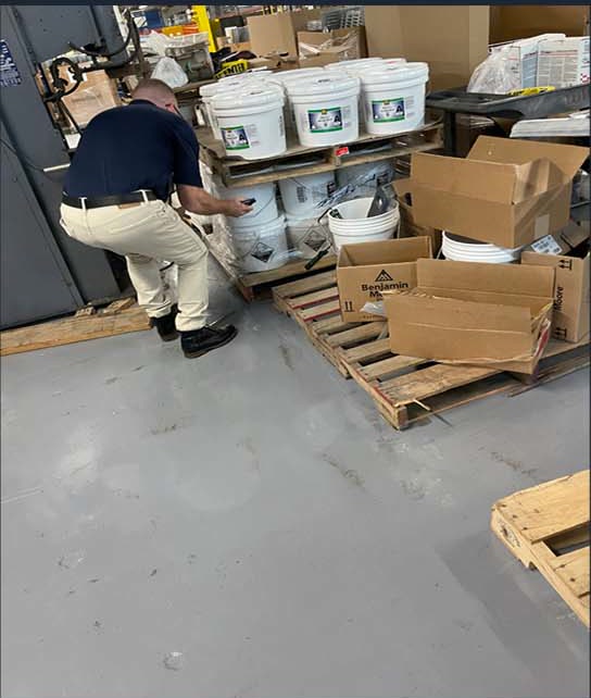 Worker handling coating supplies beside stacked buckets